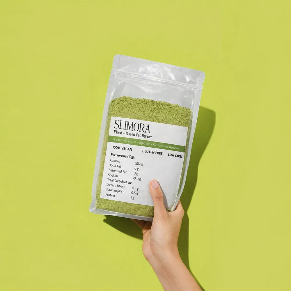 Hand holding Slimora plant-based fat burner green powder in clear resealable pouch against green background
