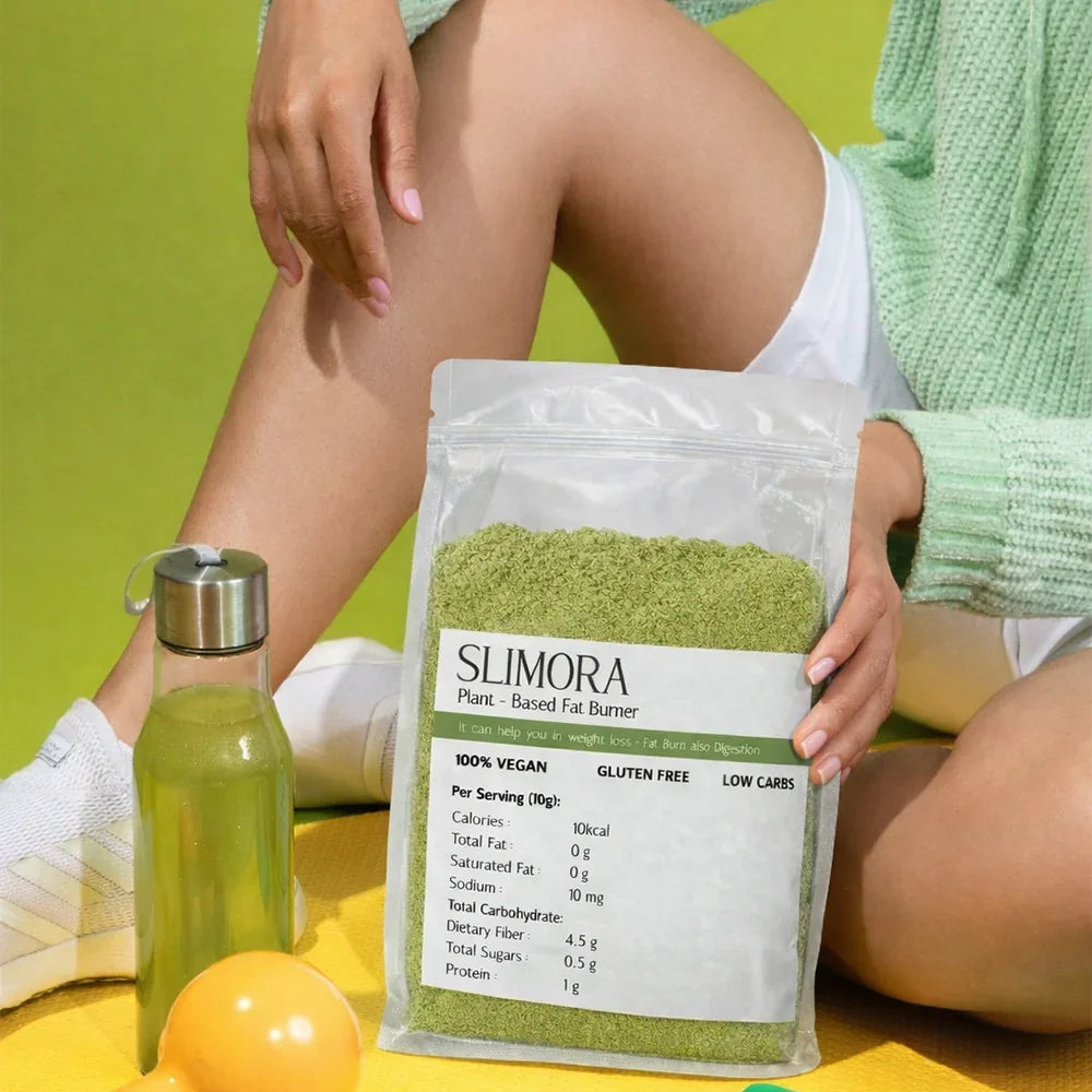 Person holding Slimora plant-based fat burner powder bag with green drink and dumbbell