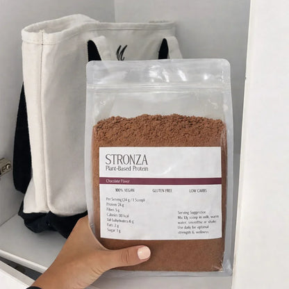Hand holding Stronza chocolate plant-based protein powder pouch, vegan gluten-free supplement