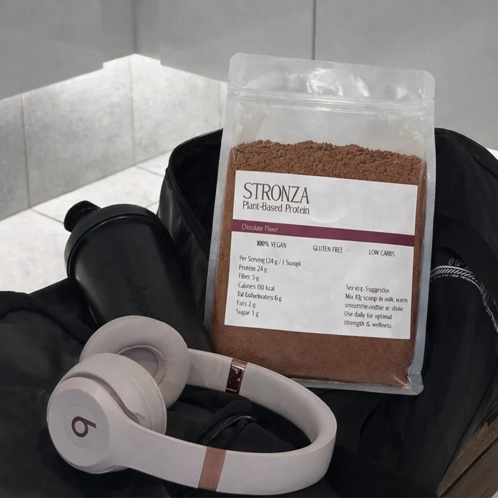 Stronza chocolate plant-based protein powder with shaker and headphones in a gym bag